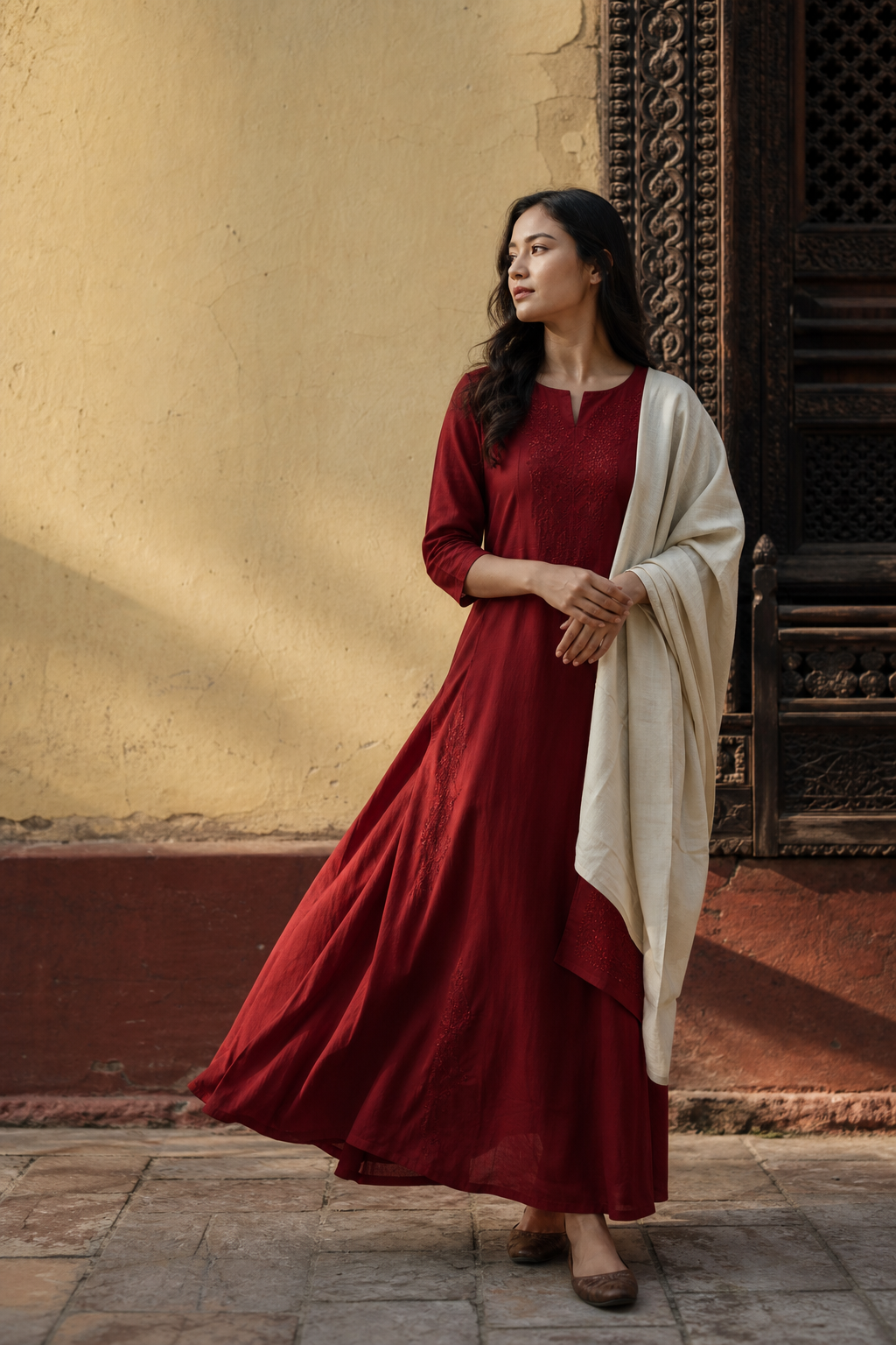 Woman wearing Geeta's deep red hand-tailored dress in a Kathmandu courtyard